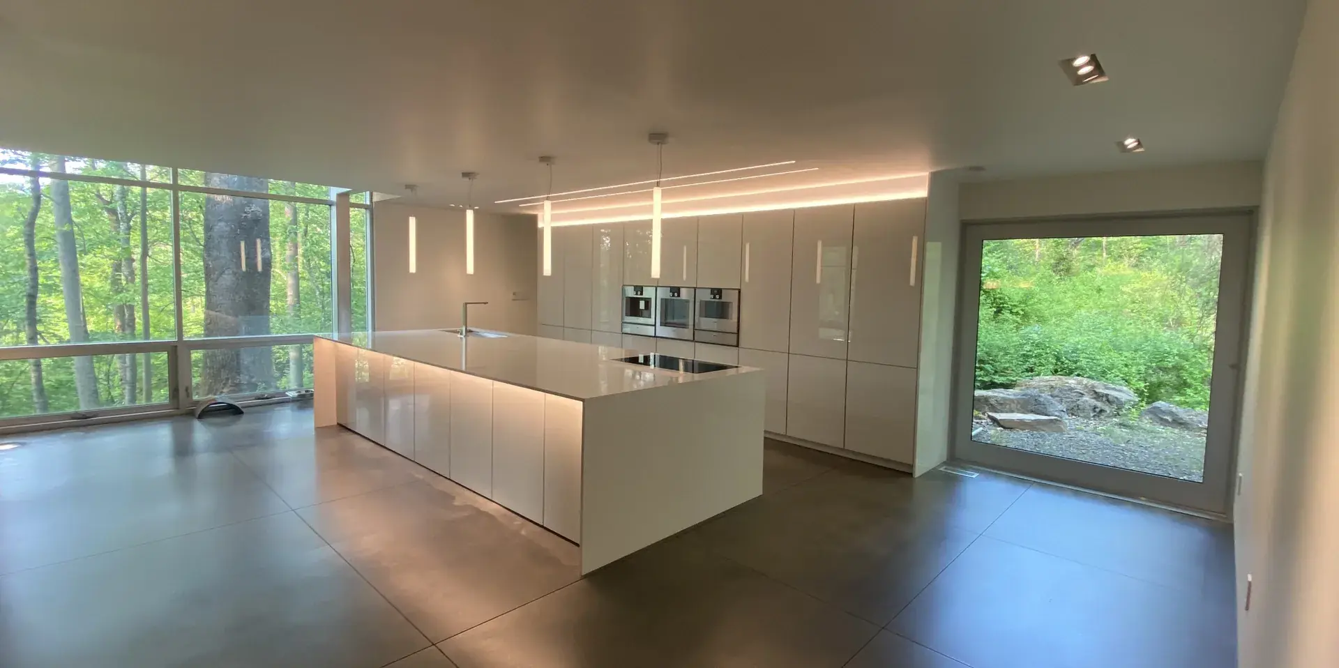 Minimalist high-end kitchen with handleless white cabinetry and floor-to-ceiling windows, designed by JMF Creative Design